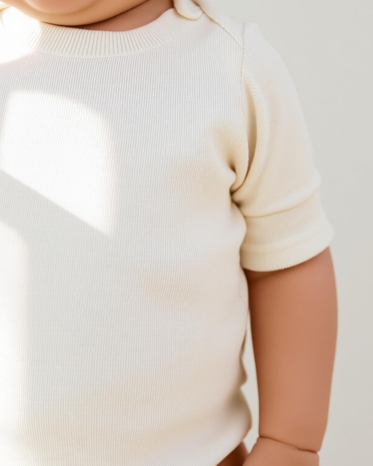 Baby wearing a Little Novice cream cotton bodysuit